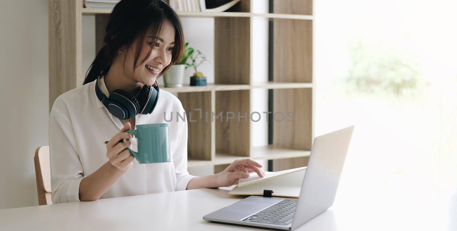 Young woman having video call on laptop computer at home by wichayada