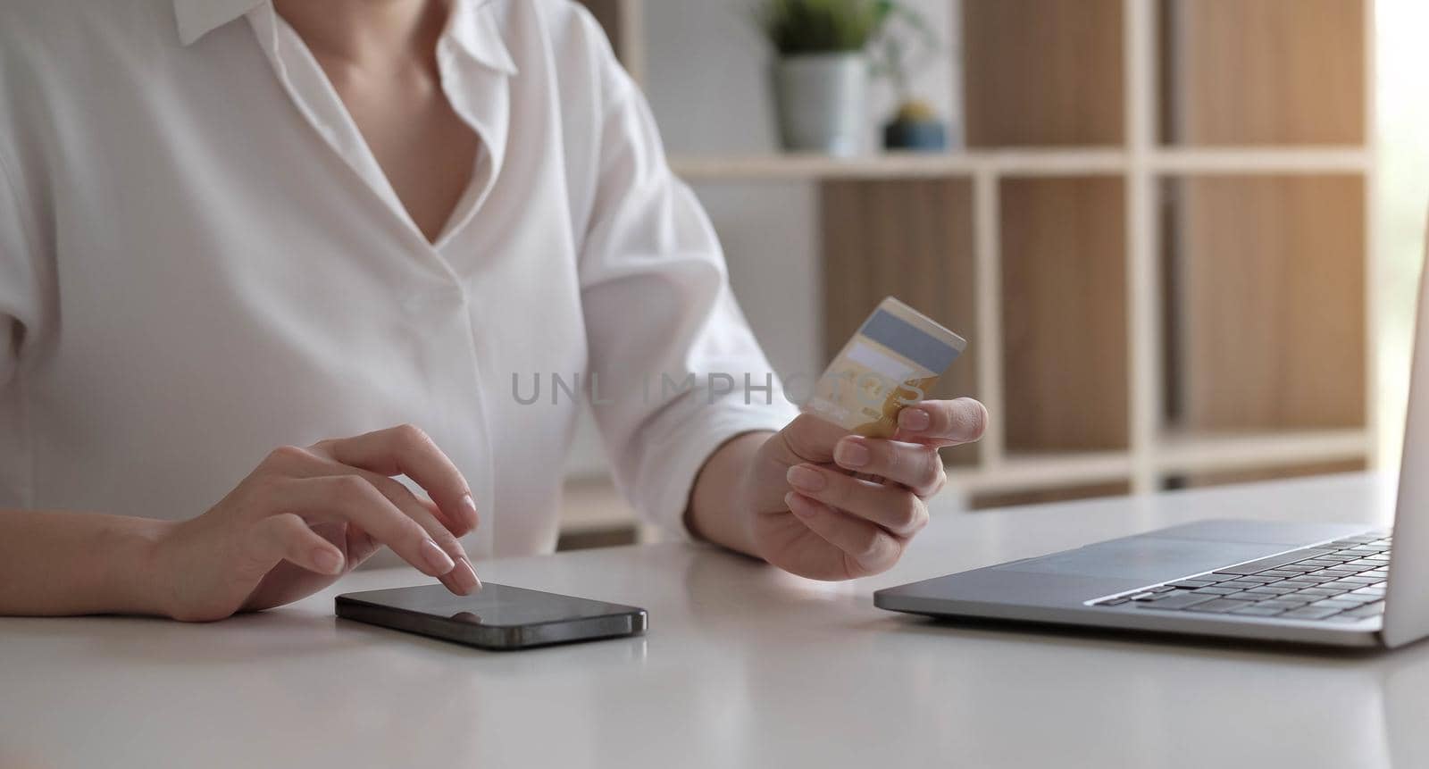 Young woman holding credit card and using laptop computer and smartphone. Online shopping concept by wichayada