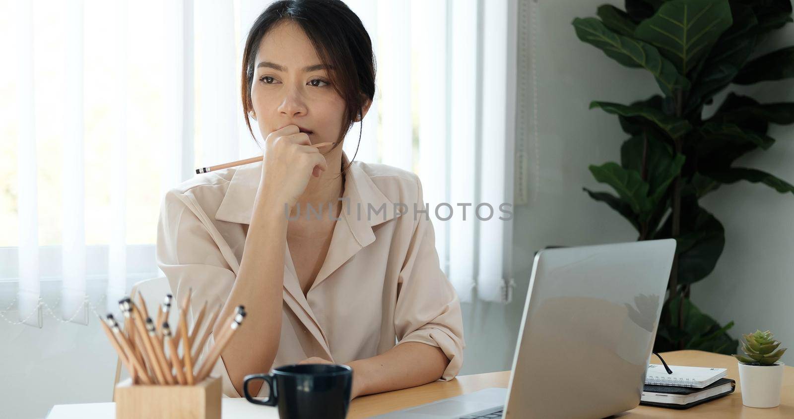 Shot of asian woman working with a stylus pen on a digital tablet and laptop computer at home.