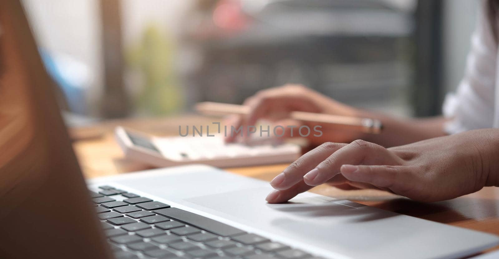 Close up of woman hand holding pencil working on calculator to calculate financial data report, accountancy document and laptop computer at office, business concept
