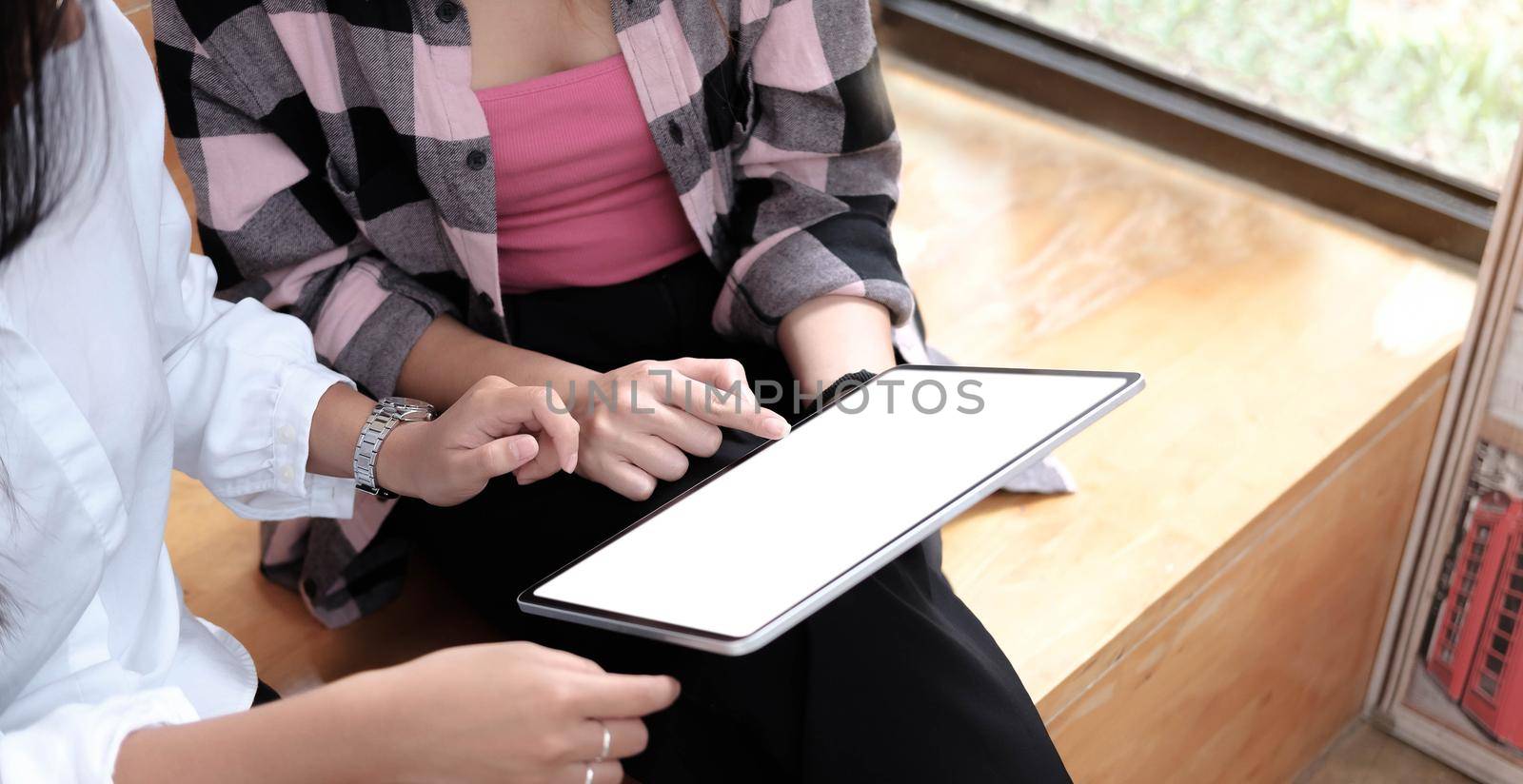two female students downloading media files on laptop computer with blank screen area for your internet advertising.