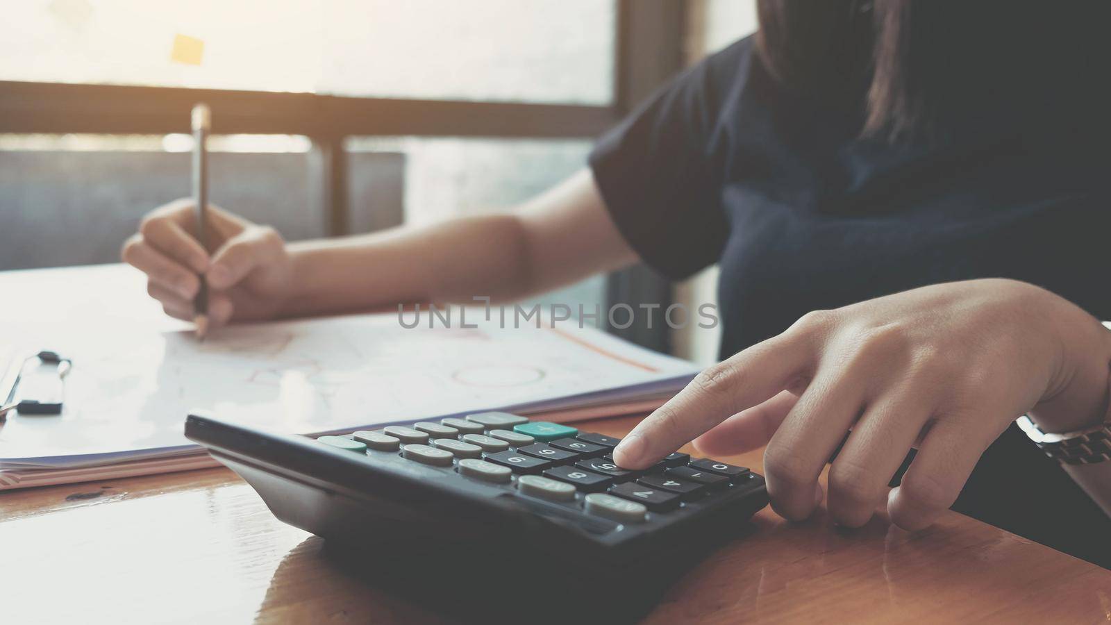 Business woman working in finance and accounting Analyze financial budget with calculator and laptop computer in the office by wichayada