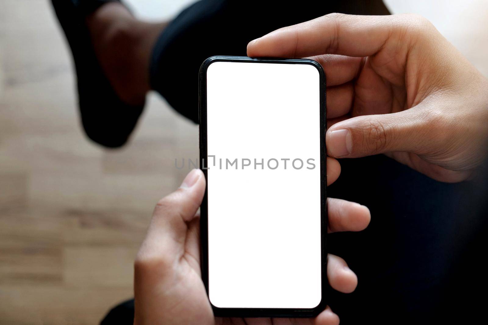 Cropped shot top view of businessman hands using smartphone mockup at the white office desk. Blank screen mobile phone for graphic display montage by wichayada