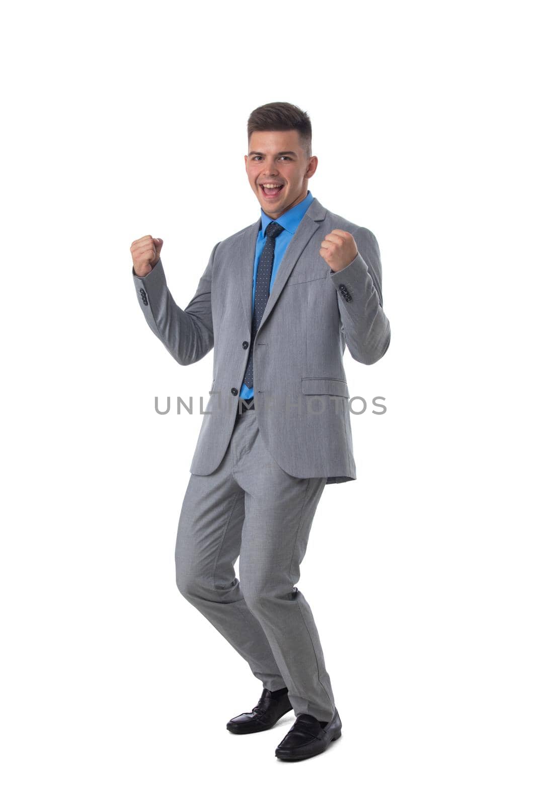 Young business man winner holding fists isolated on white background full length studio portrait