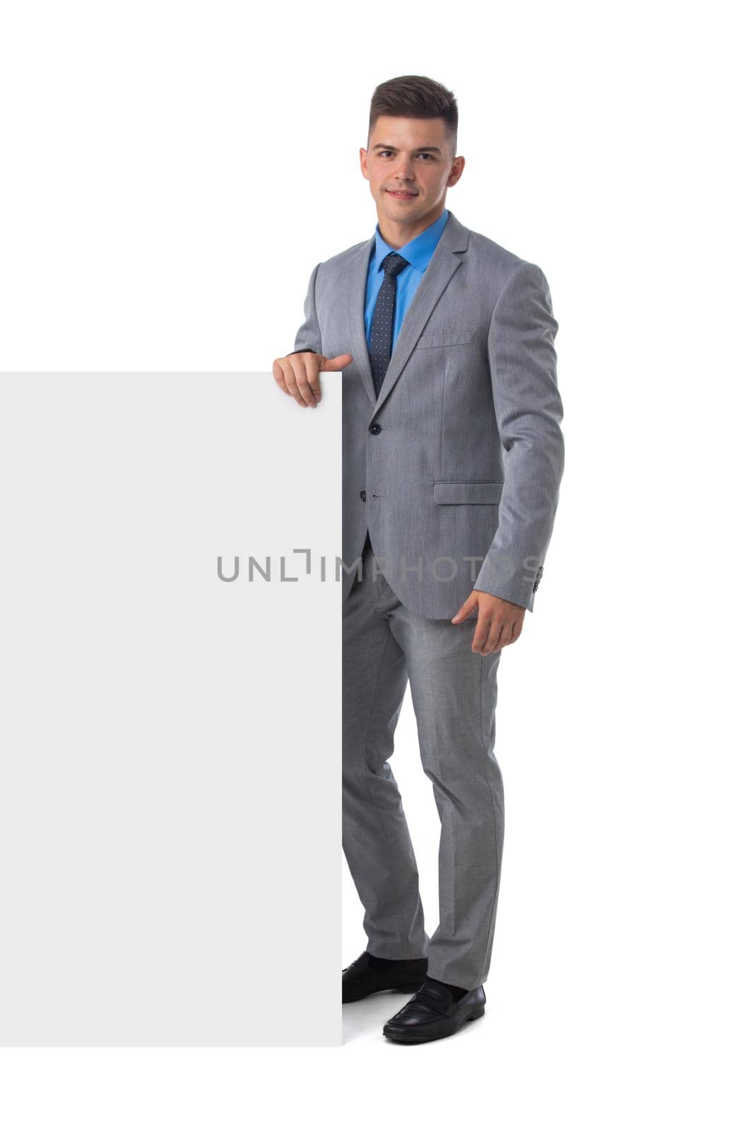 Full length portrait of young man in suit showing banner whiteboard sign isolated on white background