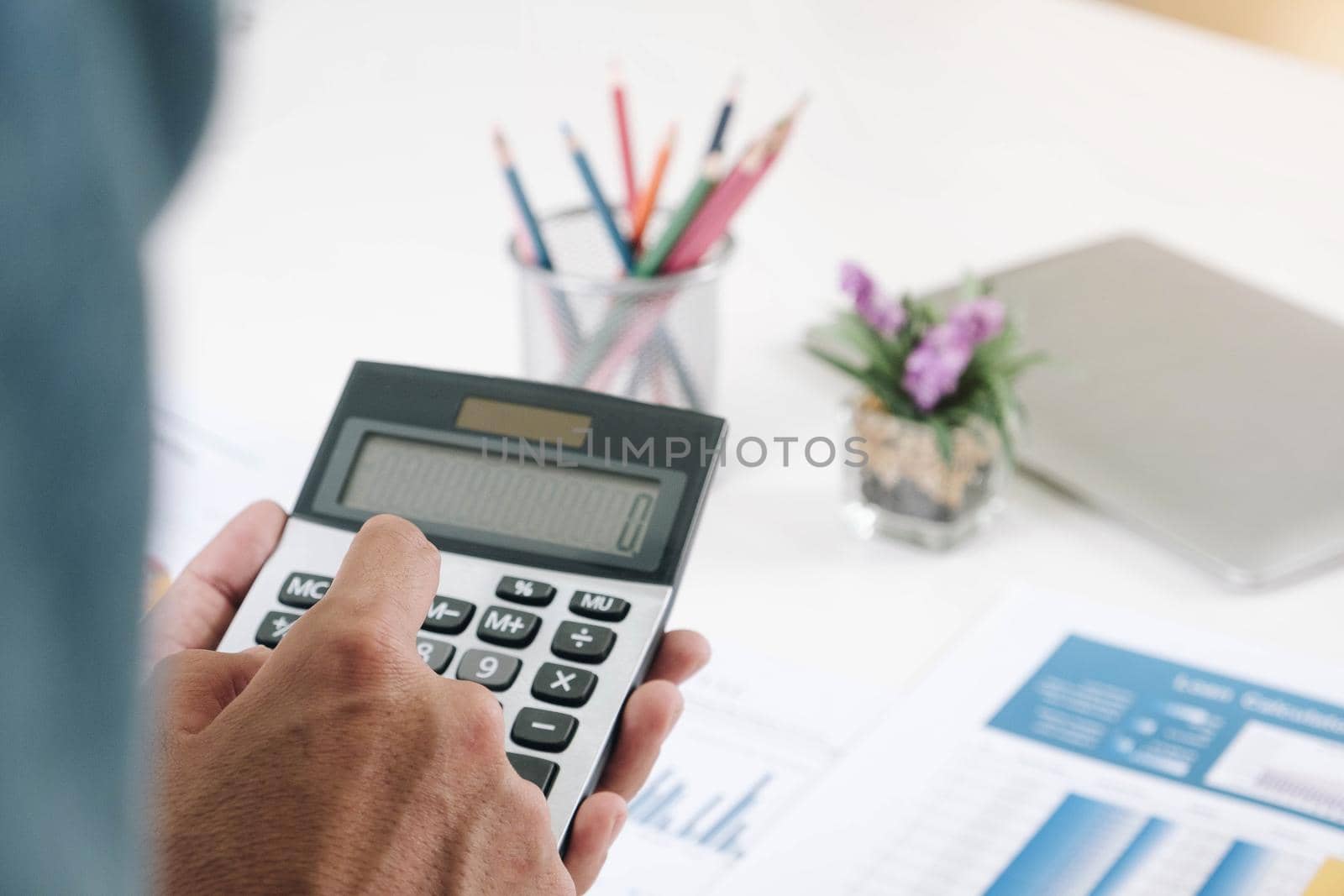 Businessman or accountant working on desk and using calculator to calculate business data, accountancy document and laptop computer in office, Business concept.
