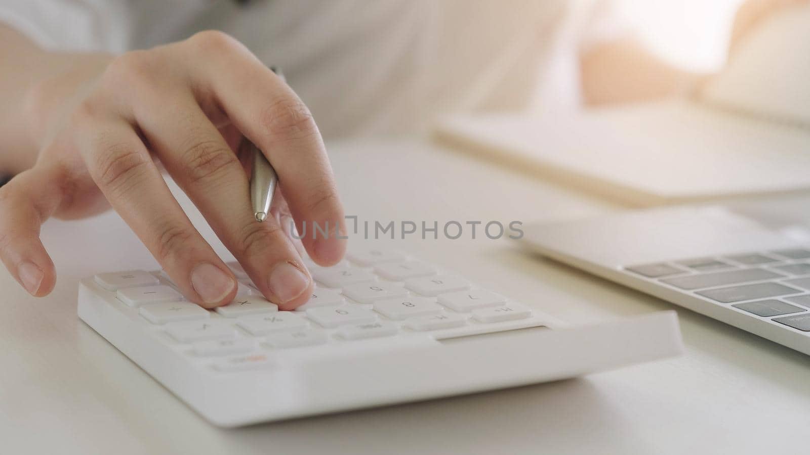 Close up Business woman using calculator and laptop for do math finance on wooden desk in office and business working background, tax, accounting, statistics and analytic research concept by wichayada
