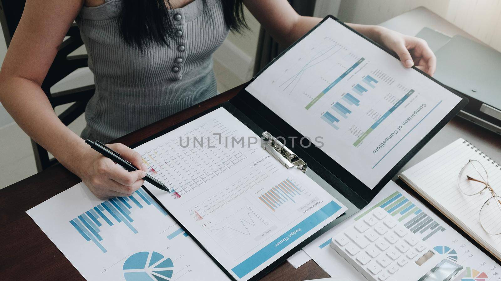 Business woman working in finance and accounting Analyze financial budget with calculator and laptop computer in the office
