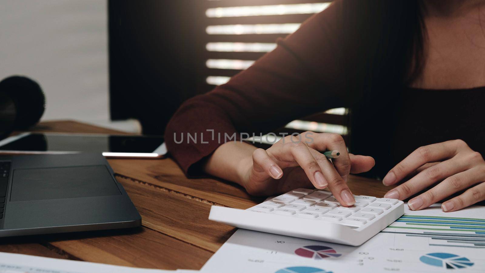 Close up Business woman using calculator and laptop for do math finance on wooden desk in office and business working background, tax, accounting, statistics and analytic research concept by wichayada