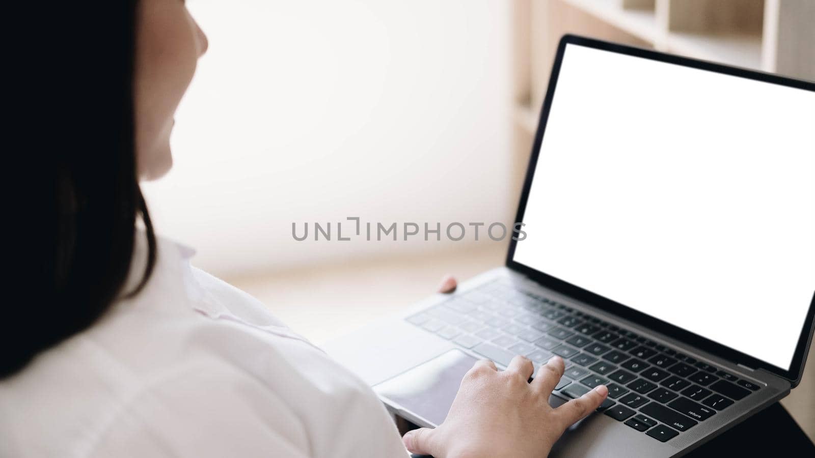 Business woman in office working on laptop with mockup blank screen. Empty copy space on monitor for business advertisement, corporate website, company financial report.  by wichayada