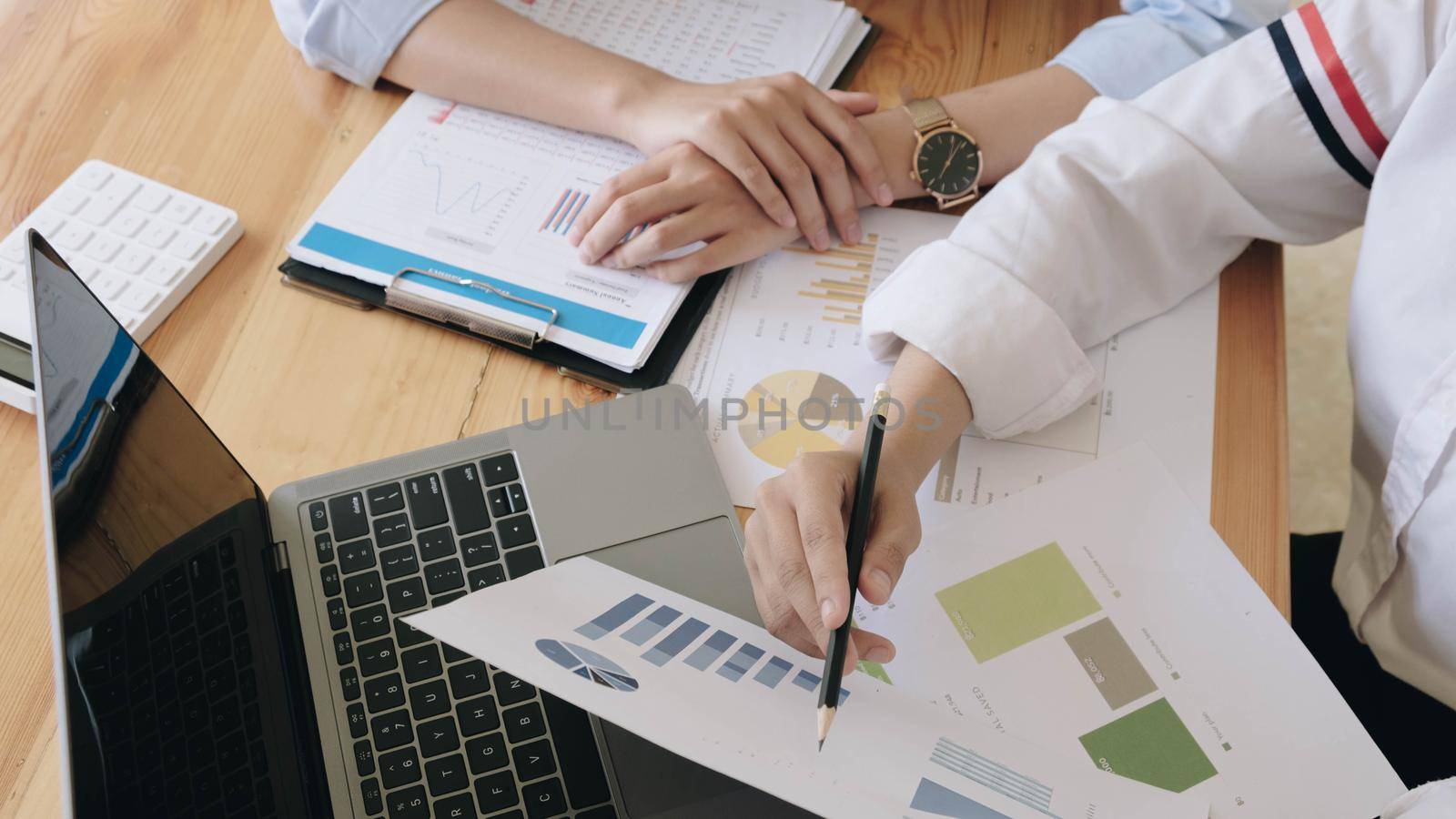 Two business woman investment consultant analyzing company annual financial report balance sheet statement working with documents graphs.  by wichayada