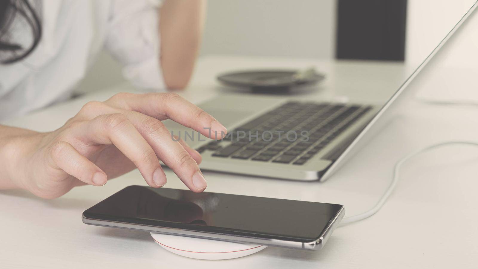 Business Woman working on workplace and mobile phone charging with wireless device
