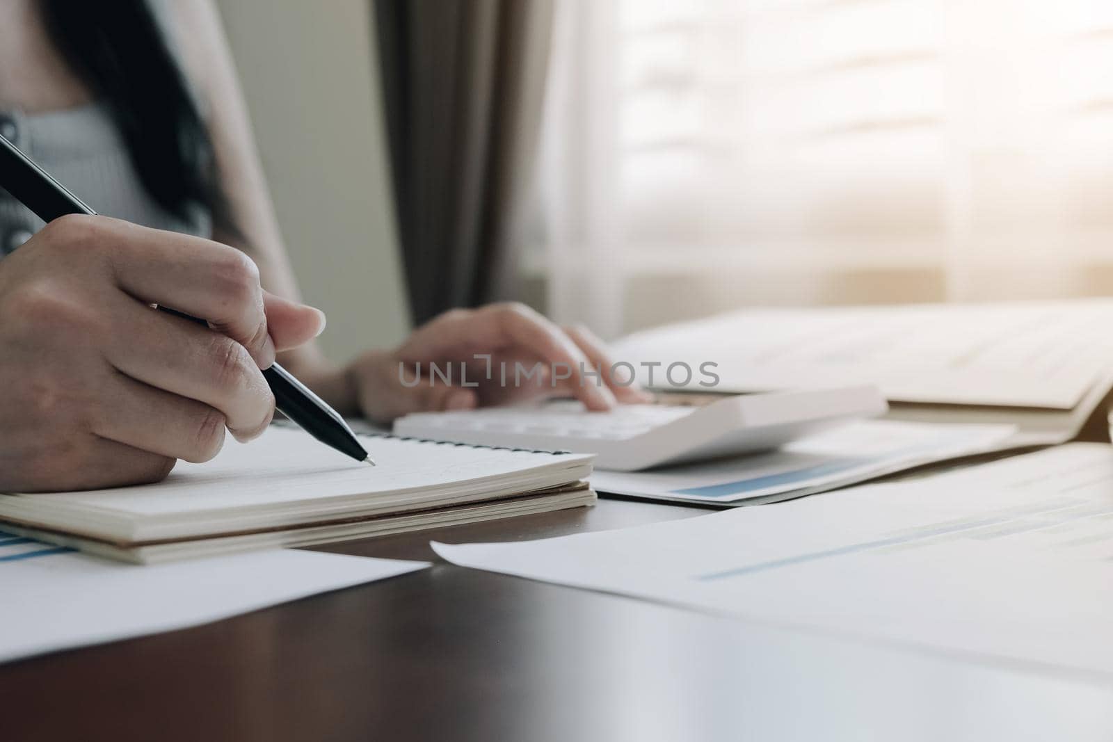 Close up of woman or accountant hand holding pencil working on calculator to calculate financial data report, accountancy document and laptop computer at office, business concept
