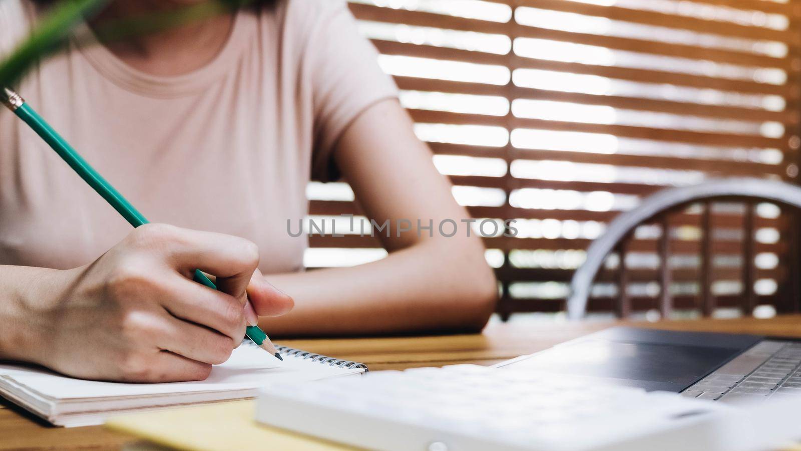 Close up of woman or accountant hand holding pencil working on financial data report, accountancy document and laptop computer at office, business concept by wichayada