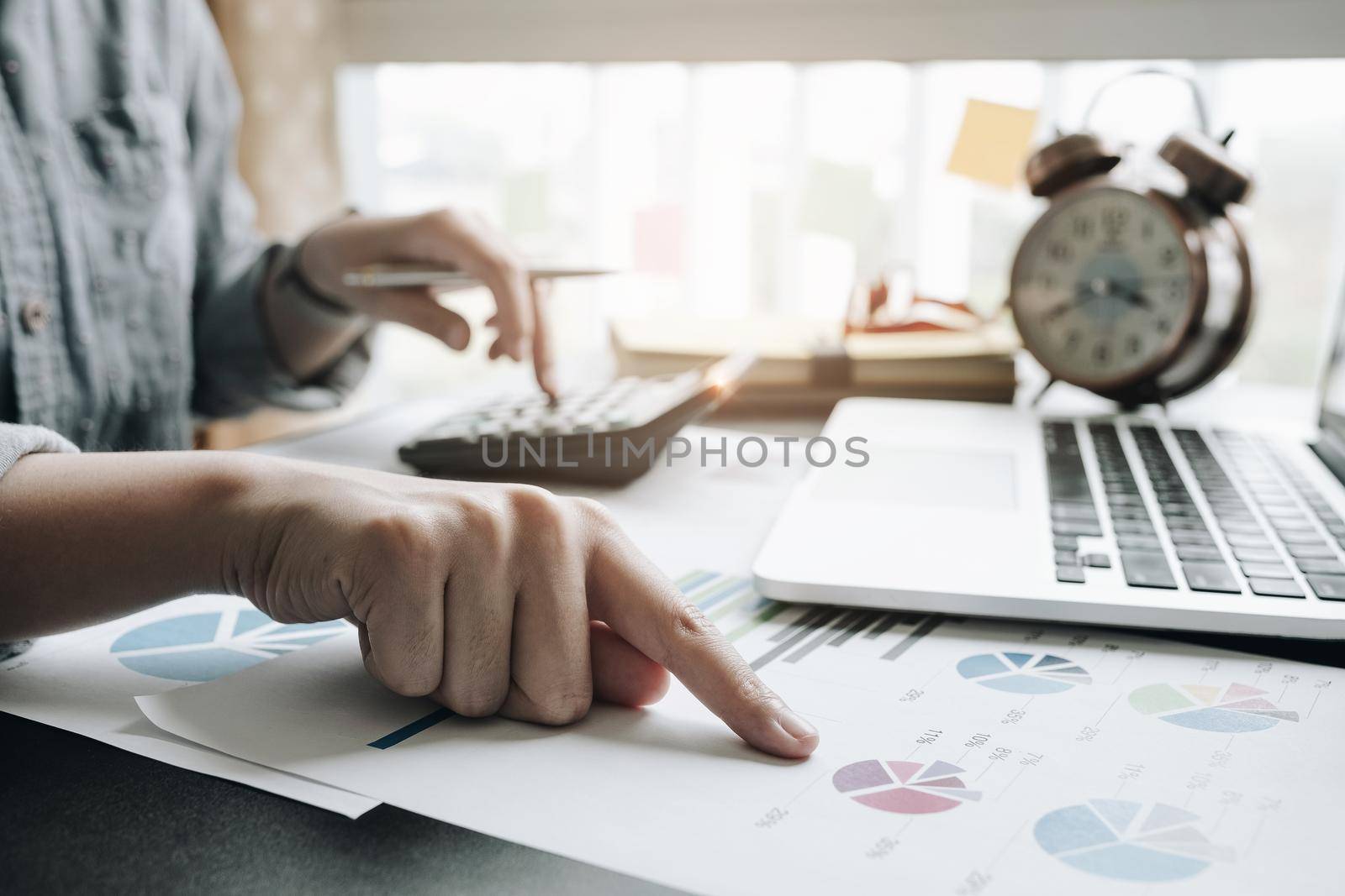Close up of businesswoman or accountant hand holding pen working on calculator to calculate business data, accountancy document and laptop computer at office, business concept
