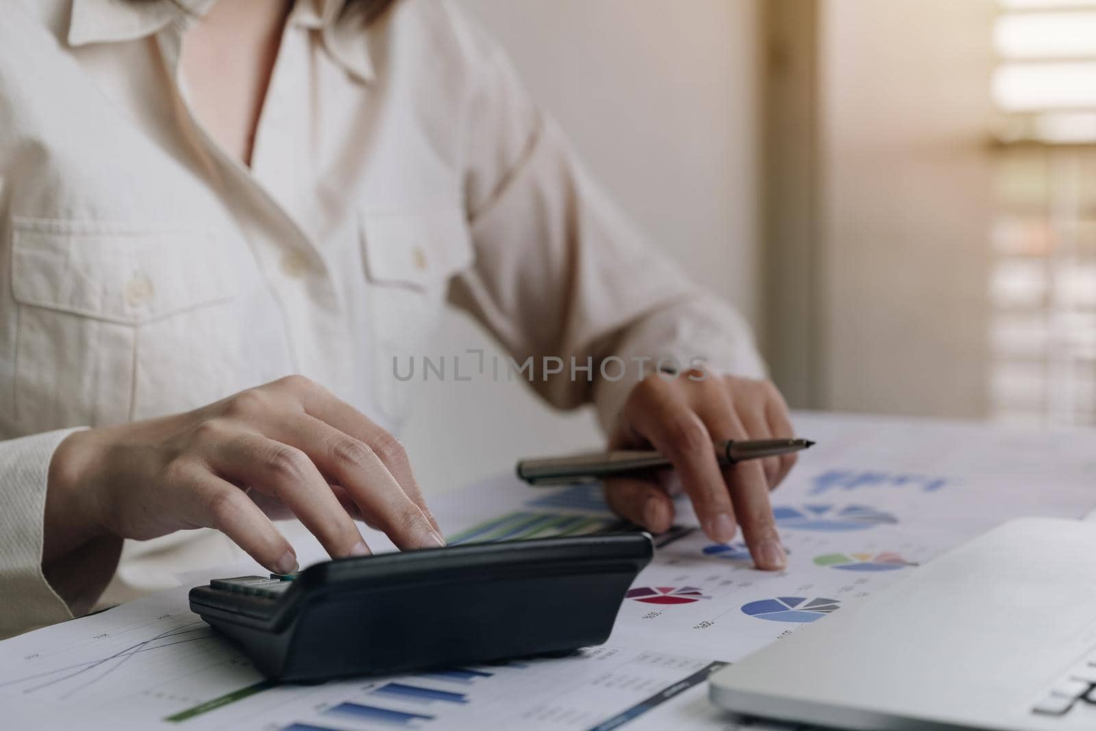Close up Business woman using calculator and laptop for do math finance on wooden desk in office and business working background, tax, accounting, statistics and analytic research concept
