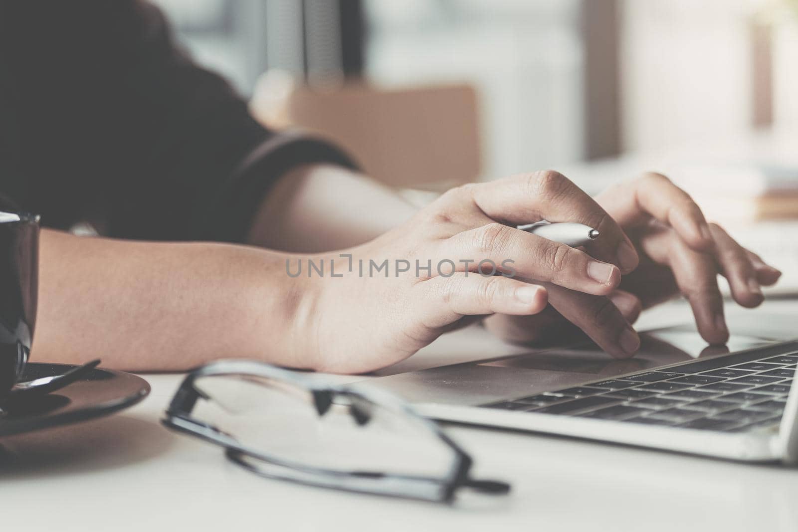 Close up of businesswoman or accountant hand holding pen working on laptop computer for calculate business data, accountancy document and calculator at office, business concept
