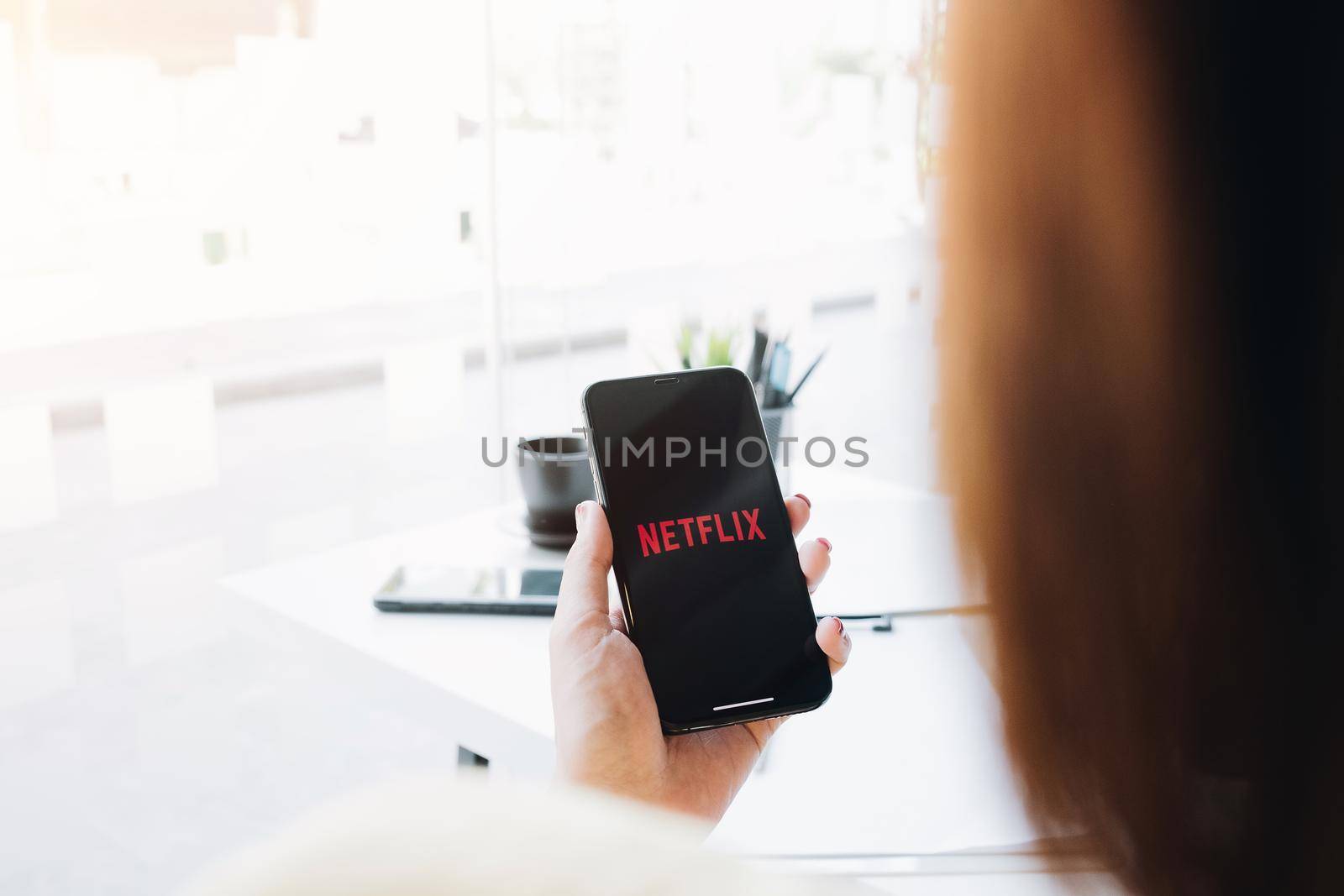 CHIANG MAI, THAILAND, MAR 12 2020: Woman hand holding Smart Phone with Netflix logo on Apple iPhone Xs. Netflix is a global provider of streaming movies and TV series. by wichayada