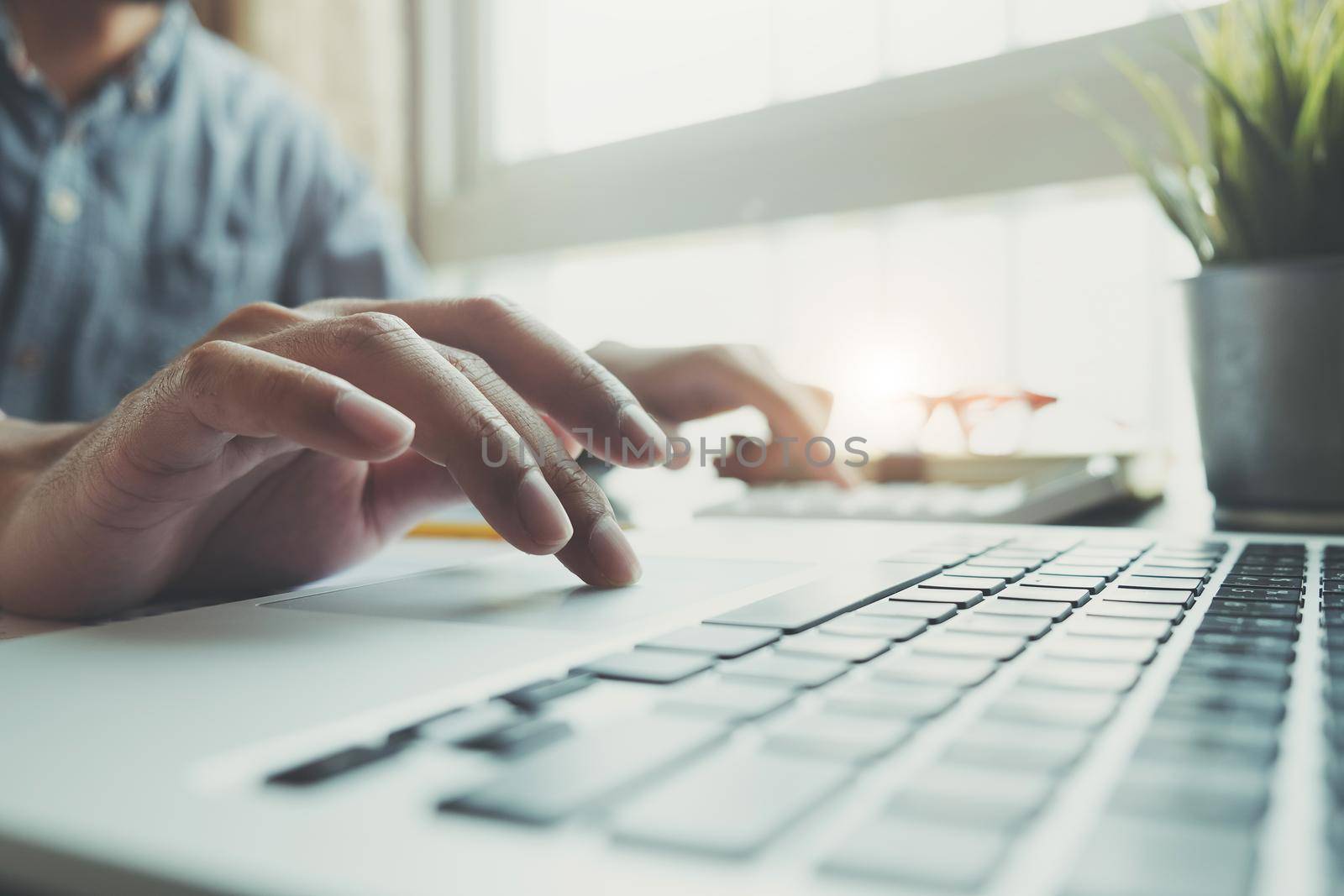 Close up Businessman using calculator and laptop for do math finance on wooden desk in office and business working background, tax, accounting, statistics and analytic research concept by wichayada