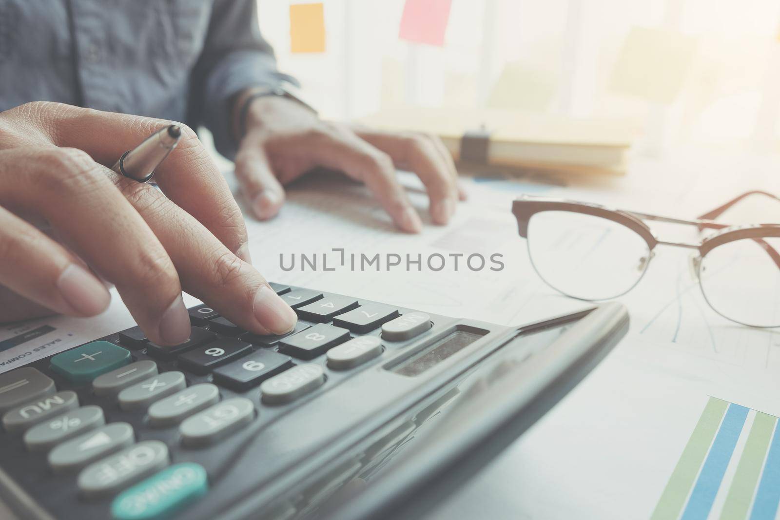 Close up Businessman using calculator and laptop for do math finance on wooden desk in office and business working background, tax, accounting, statistics and analytic research concept