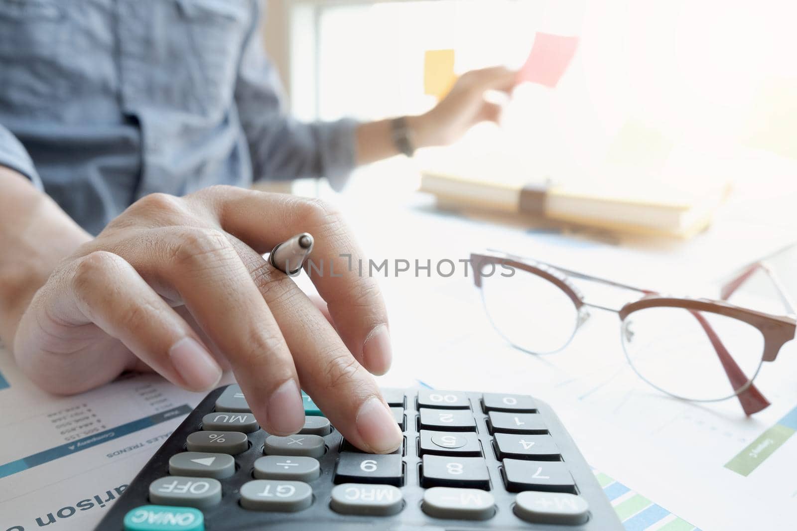 businessman or accountant hand working on calculator to calculate financial data report, accountancy document and laptop computer at office by wichayada