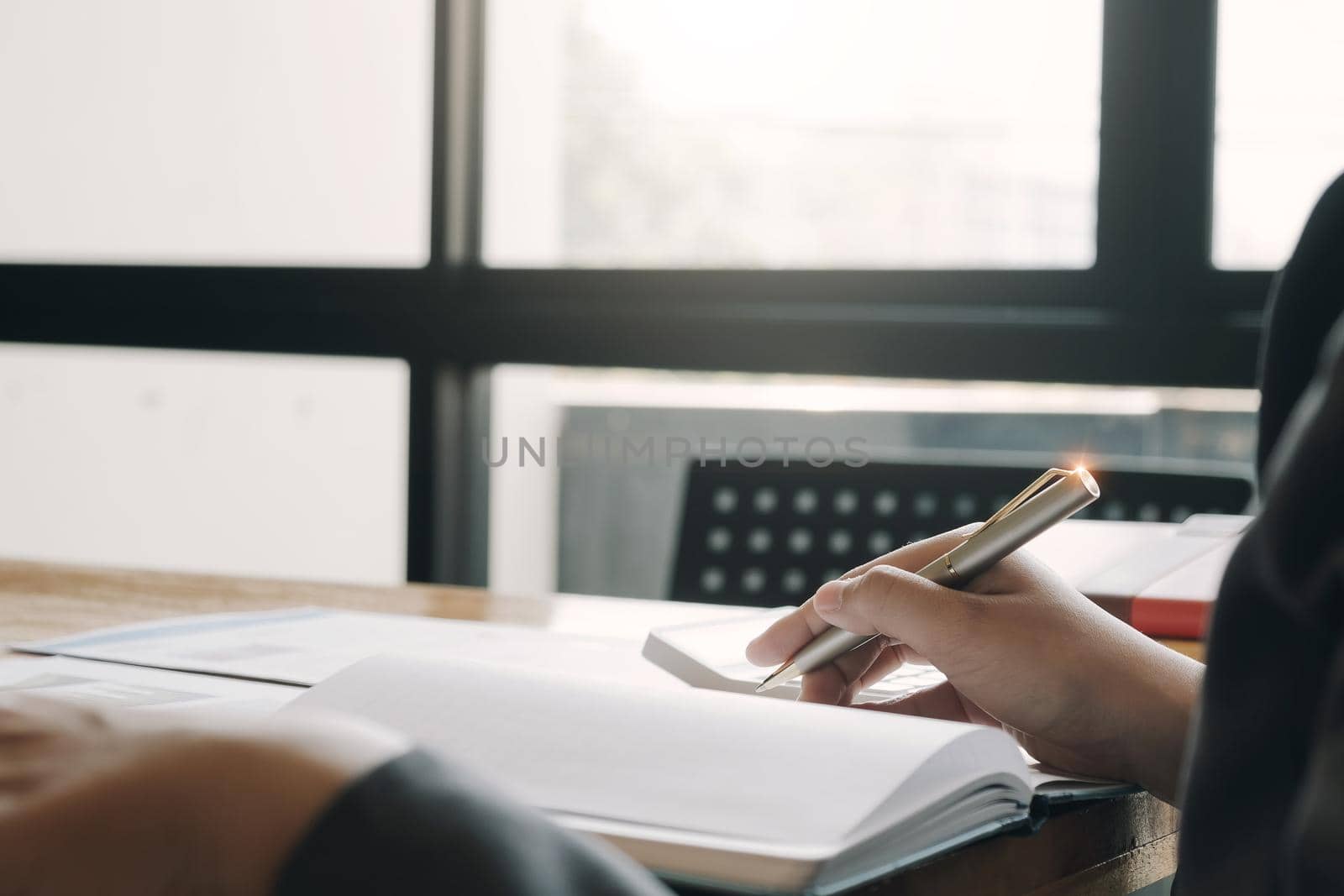 Close up of businessman or accountant hand holding pen working on laptop computer for calculate business data, accountancy document and calculator at office, business concept by wichayada