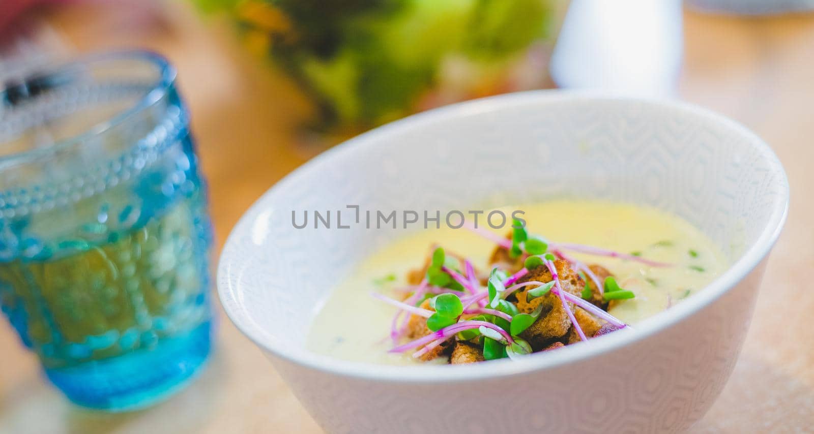Close up of fresh broccoli soup with crunchy croutons and radish sprouts in white ceramic bowl