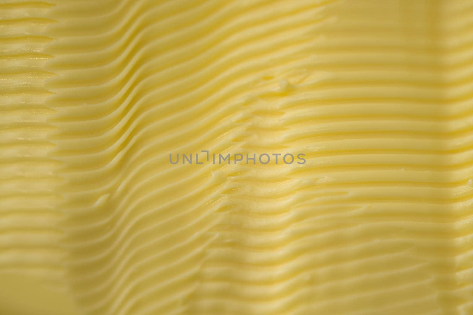 Full frame background texture of ripples in yellow margarine. Possible healthier food choice to traditional butter. Manufactured spreadable diary.