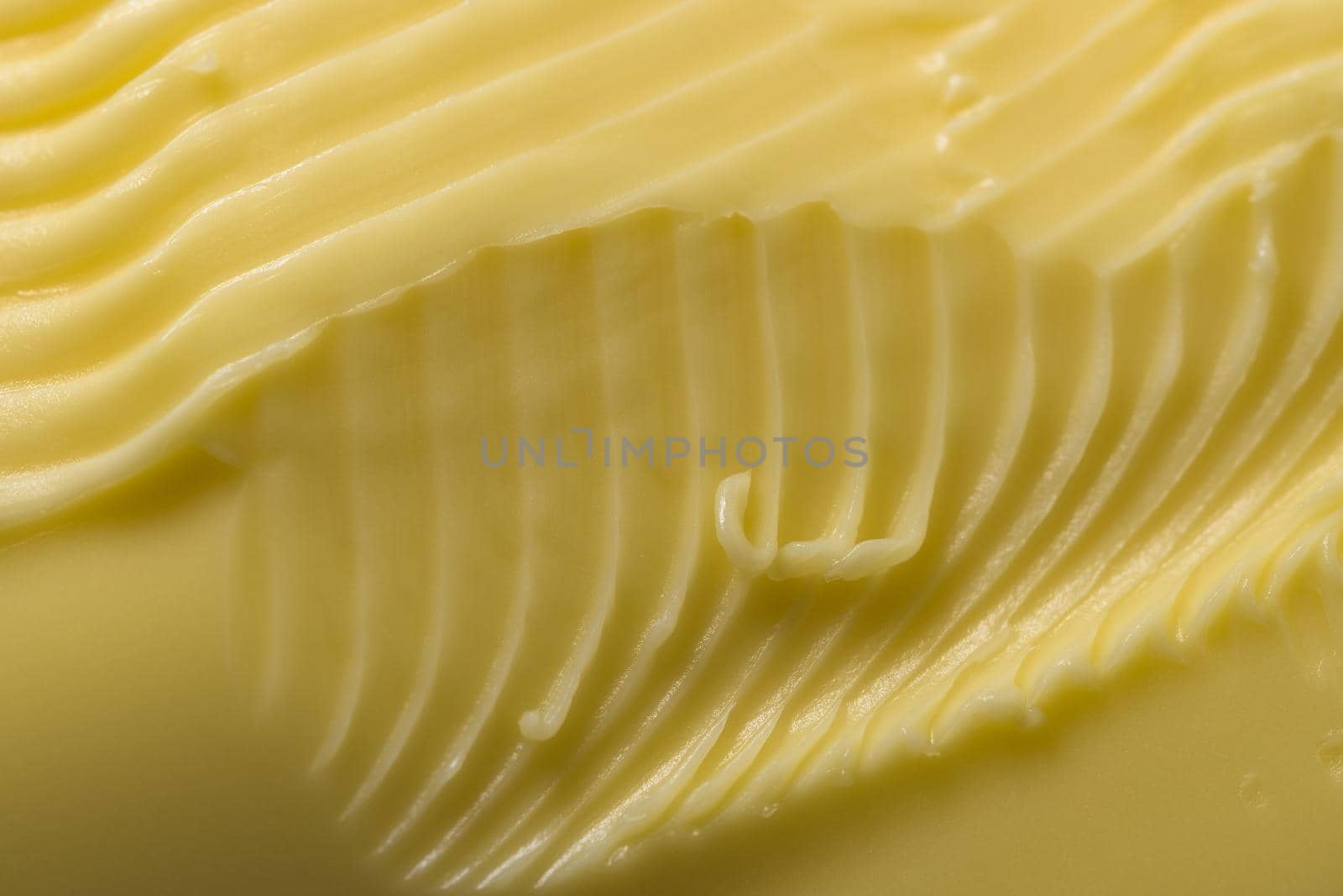 Super close up macro background of intricate grooves and swirls of margarine. Made by a serrated kitchen knife that was swept over the surface.