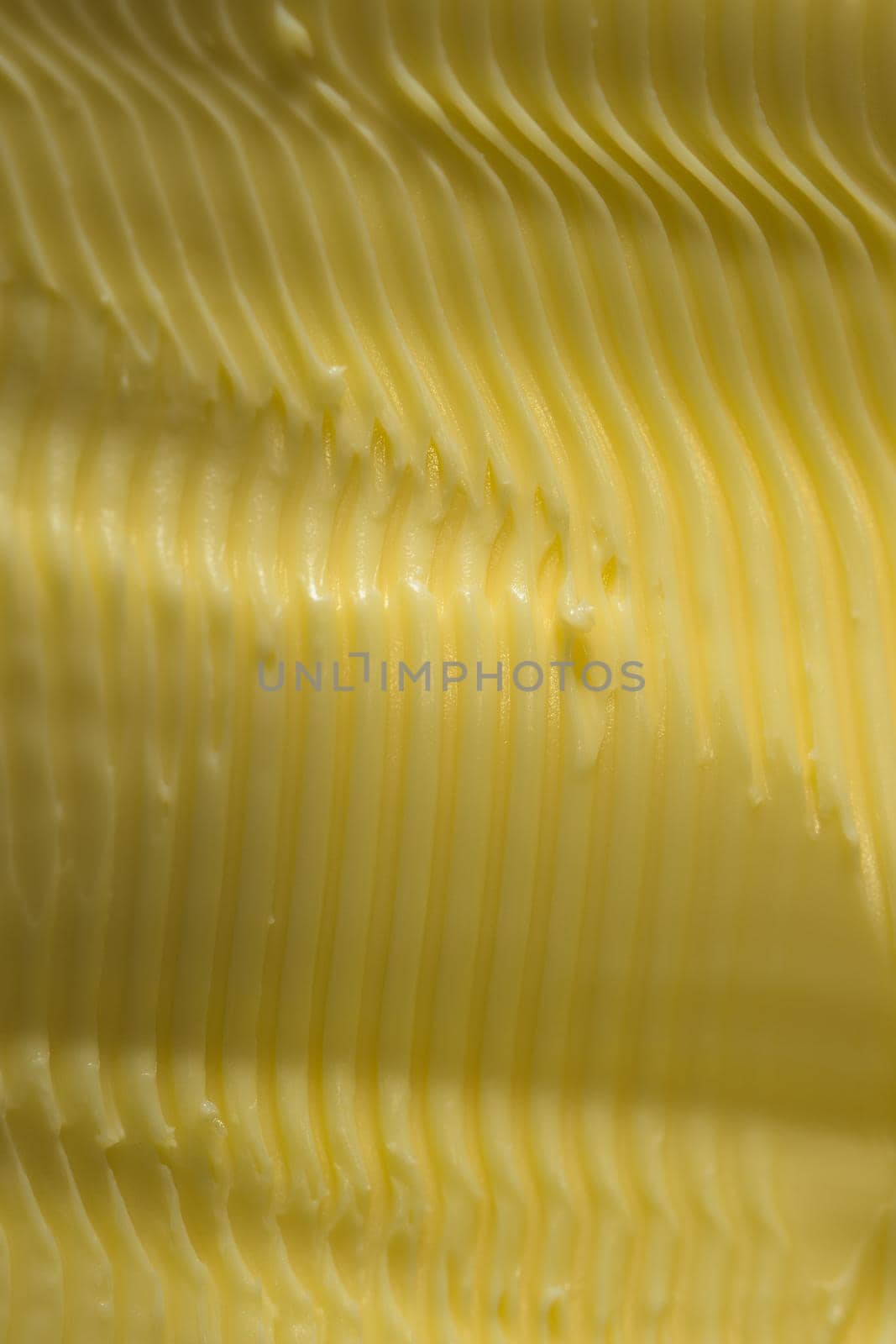 Vertical food texture image. Full frame margarine, textured into wavy ridges using a knife. Commonly found in kitchens as an alternative to butter
