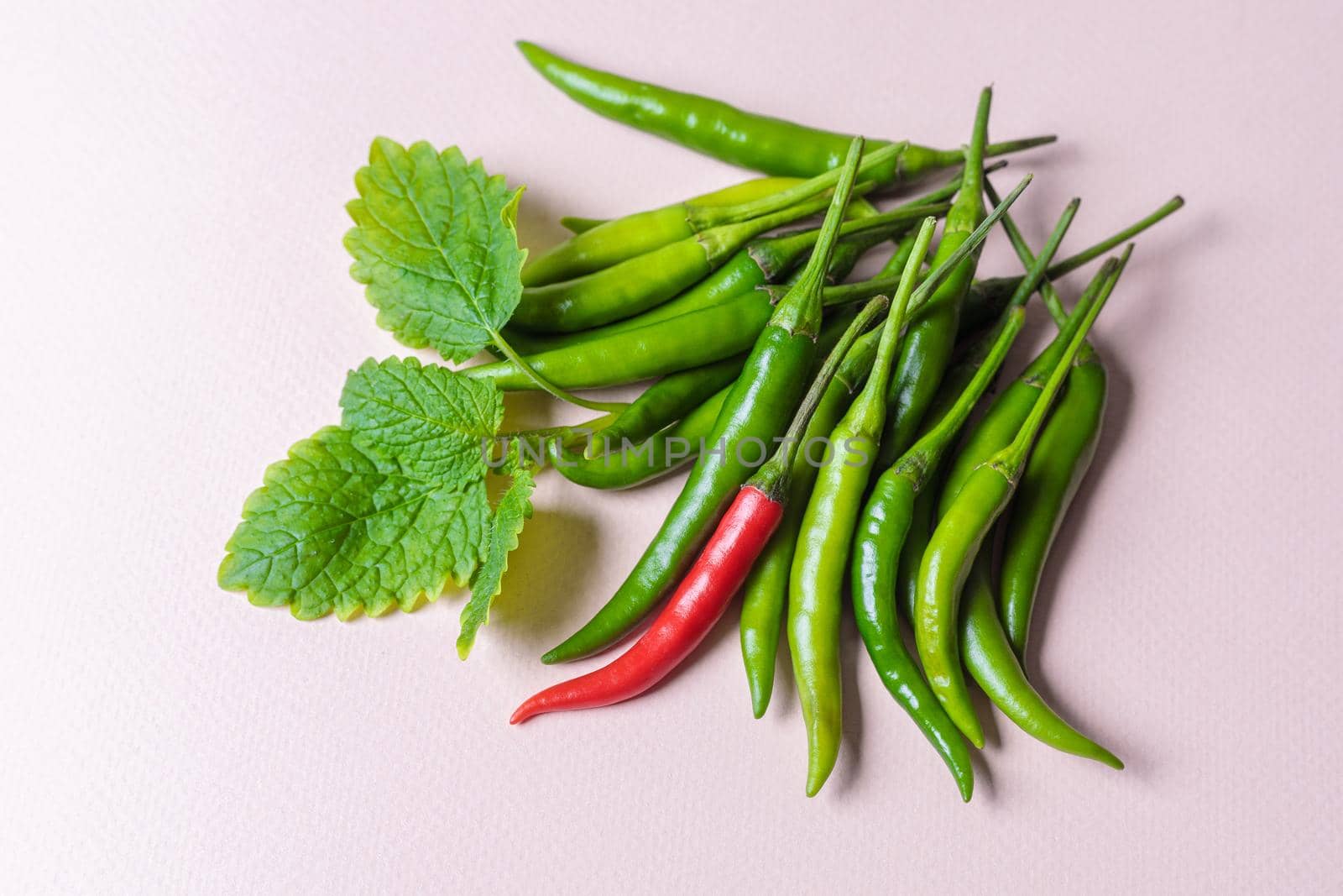 Slide of green chili peppers with one red on a light background. View from above.