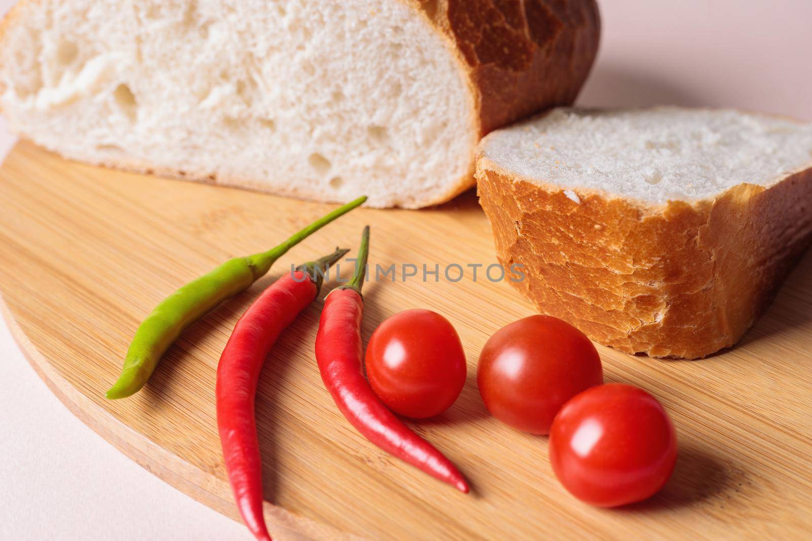 Sliced pieces of white bread with red peppers and tomatoes on a cutting board by Yurich32