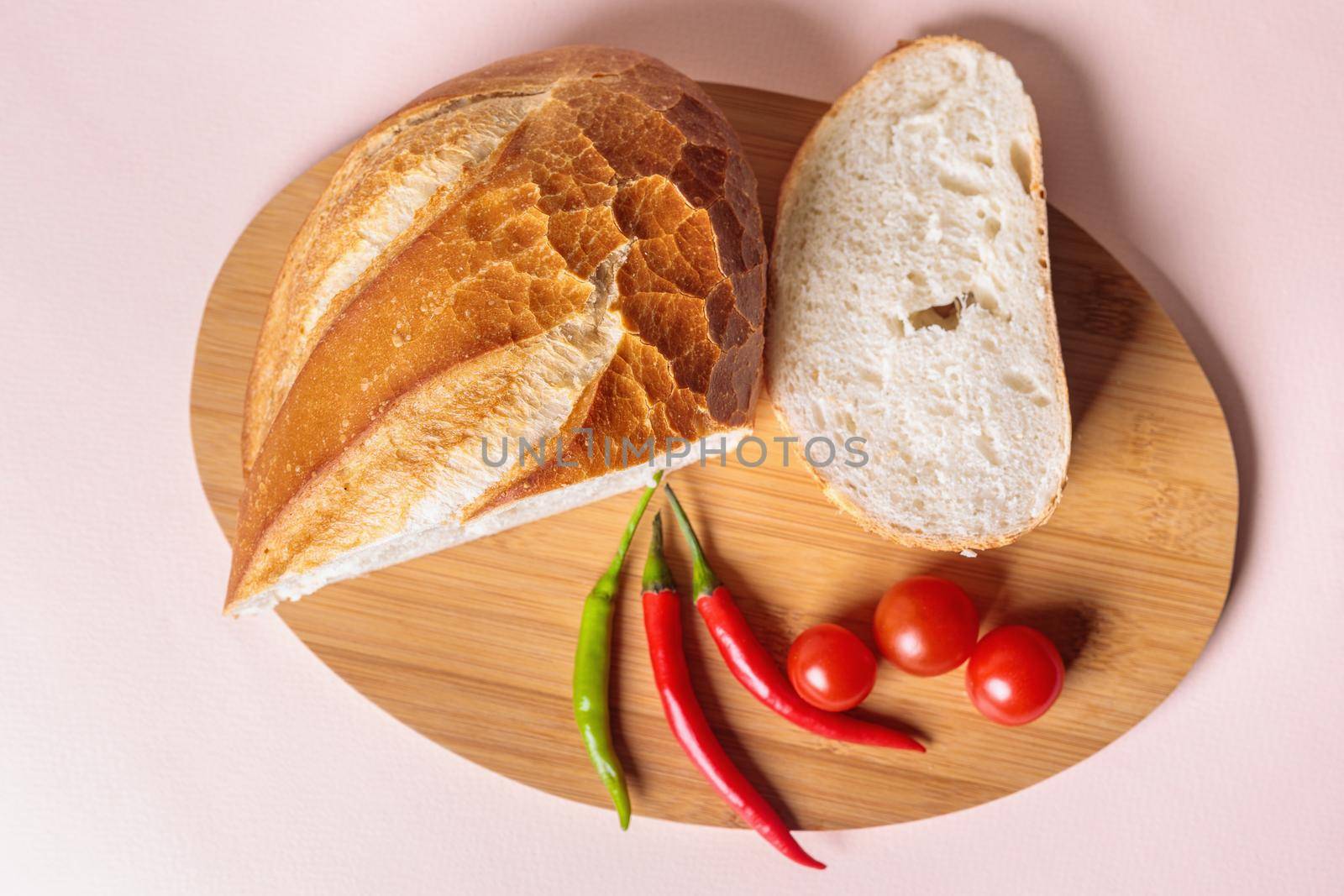 Sliced pieces of white bread with red peppers and tomatoes on a cutting board by Yurich32