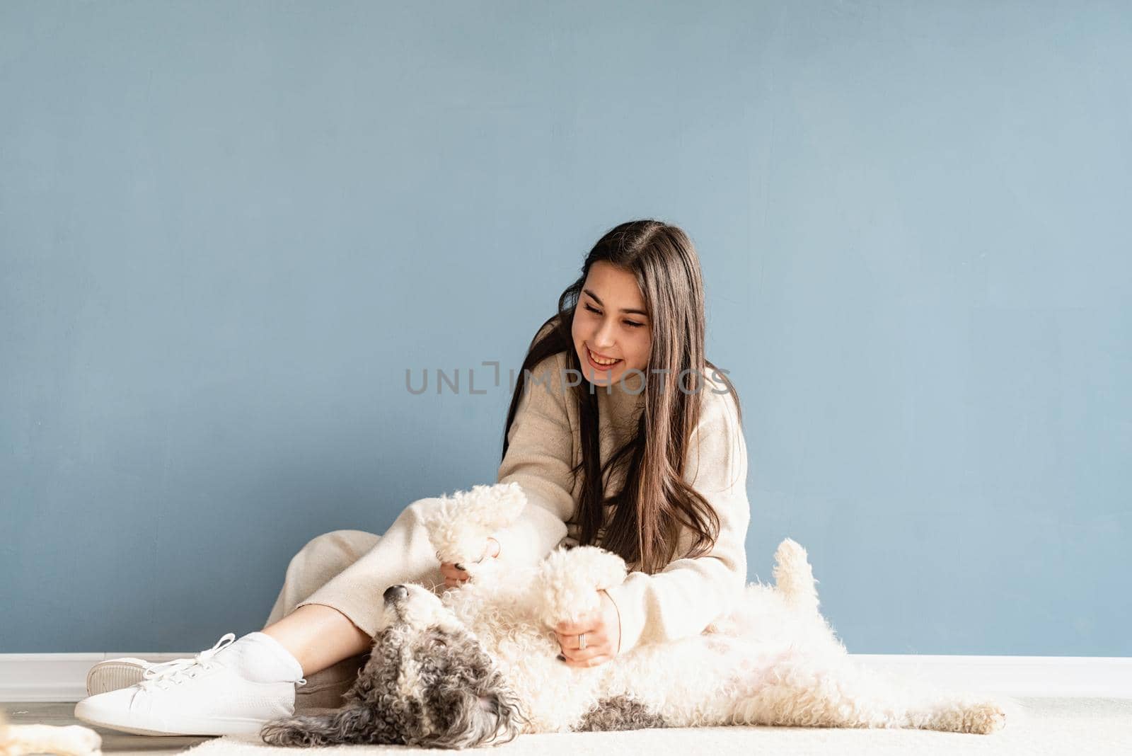 Beautiful woman with playful dog embracing at home by Desperada