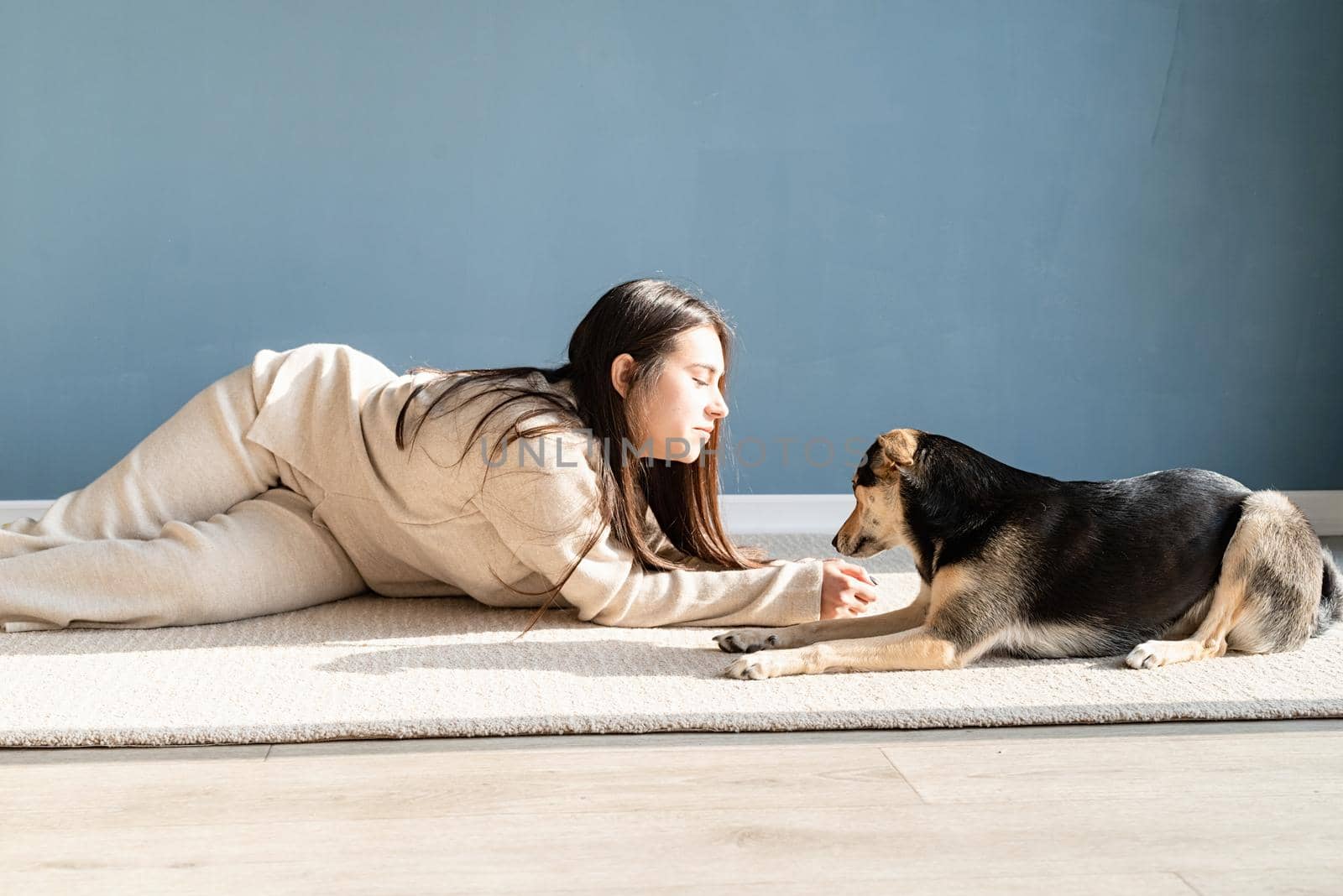 Beautiful woman with playful dog embracing at home by Desperada