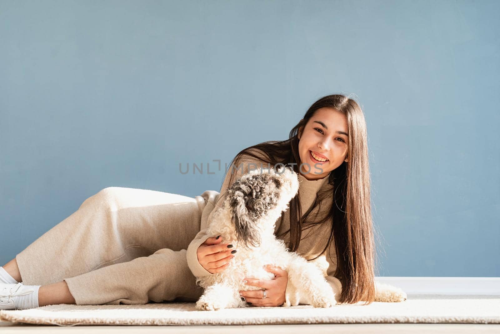 Beautiful woman with playful dog embracing at home by Desperada