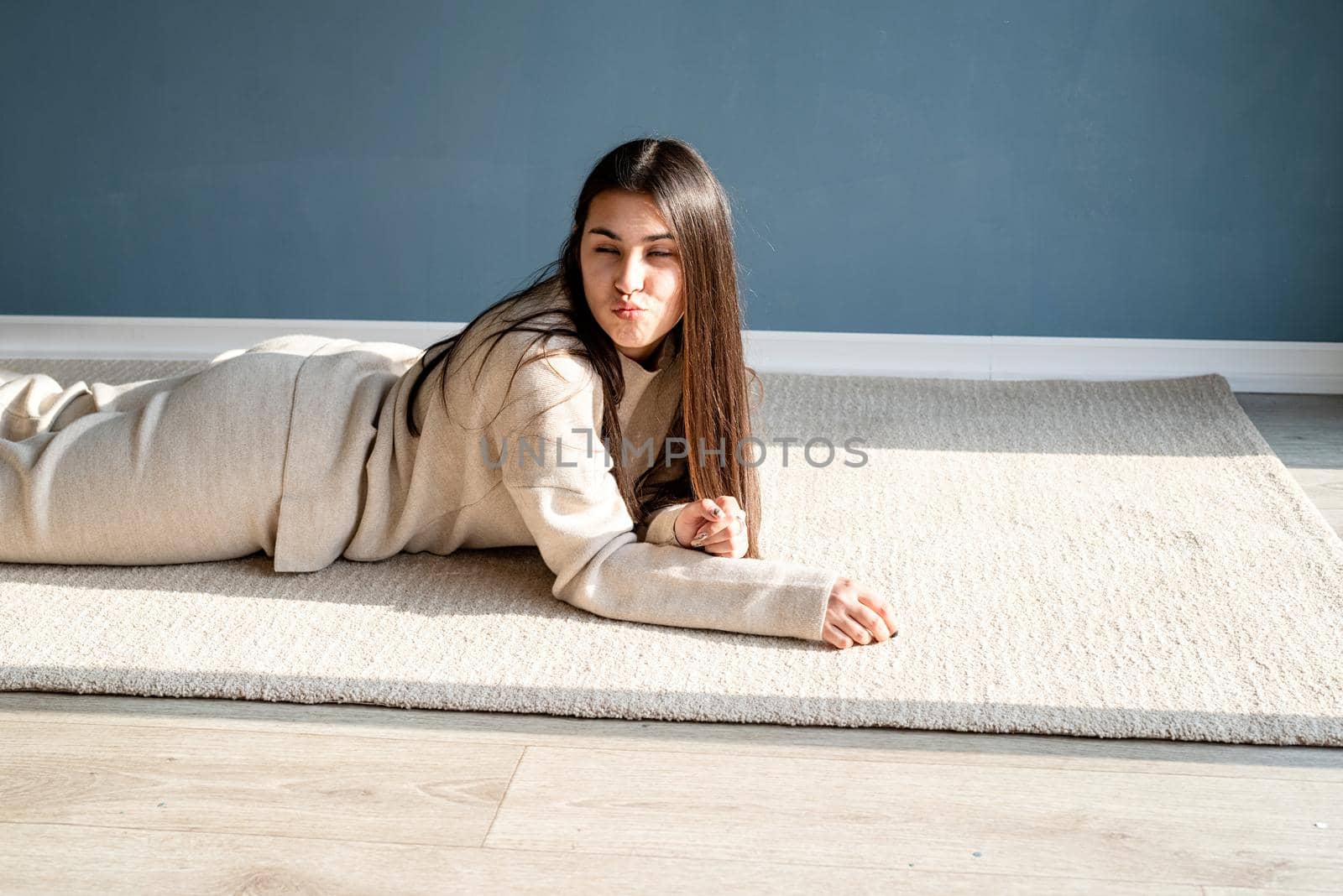 young woman blowing a kiss lying on the rug by Desperada