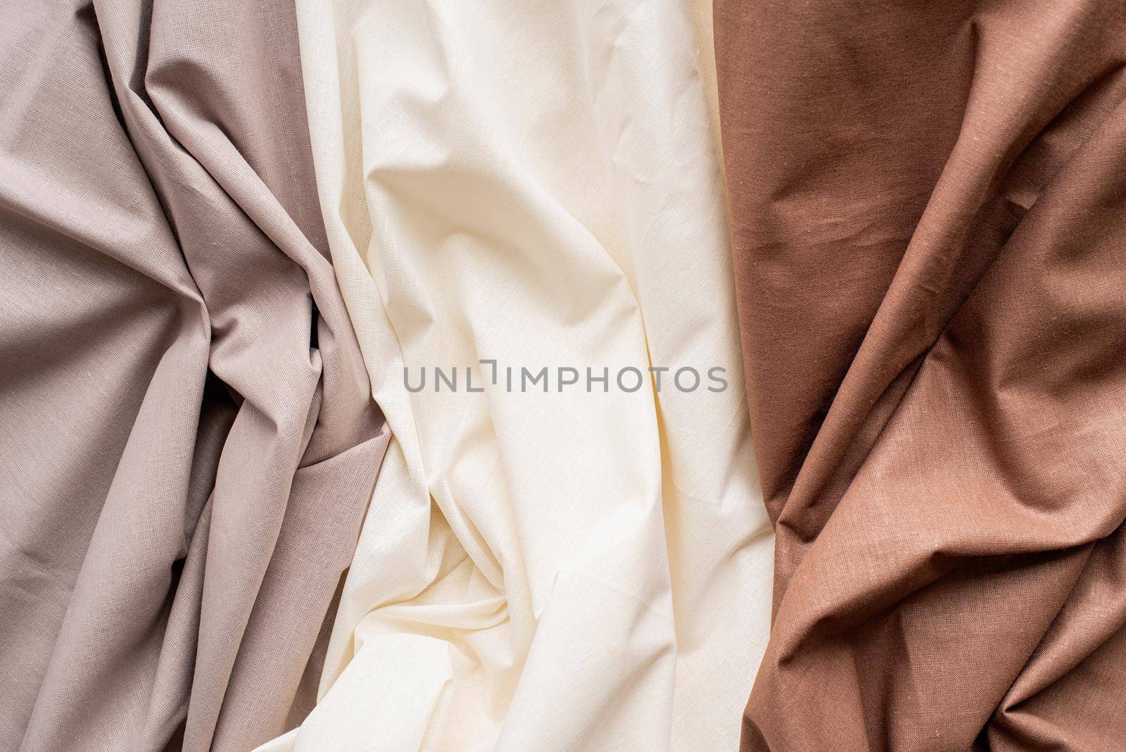 Closeup of rippled white, gray and brown silk fabric. Abstract texture background