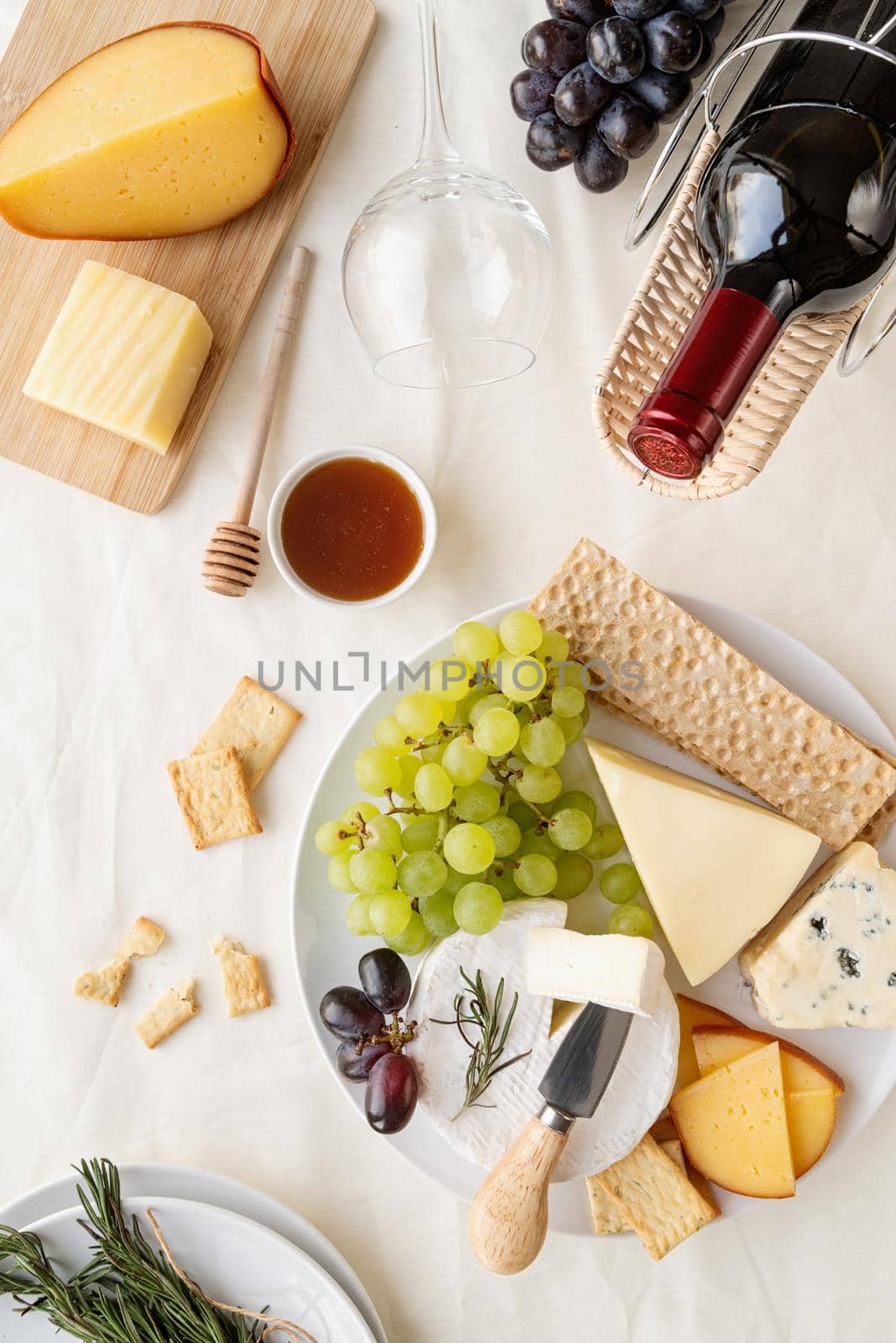 Cheese plate: Maasdam, Camembert cheese, blue cheese, bread , grapes, rosemary, wine, honey, grapes on table