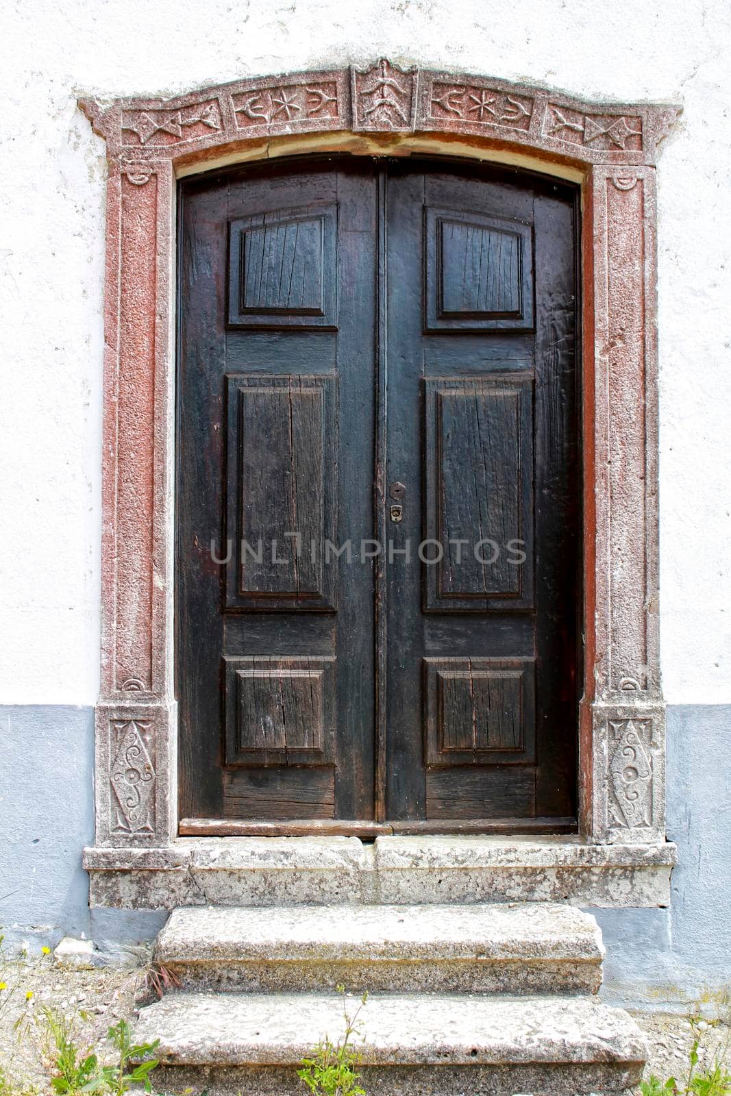 Old wooden door with tiled facade in Lisbon. Wrought metal details on the door.