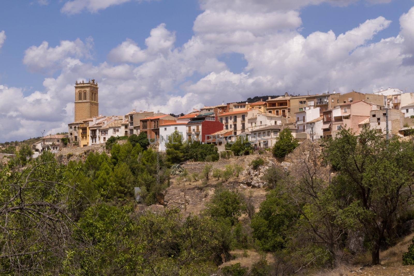 Wide-shot of an old town on a hill with a clock tower on a sunny day