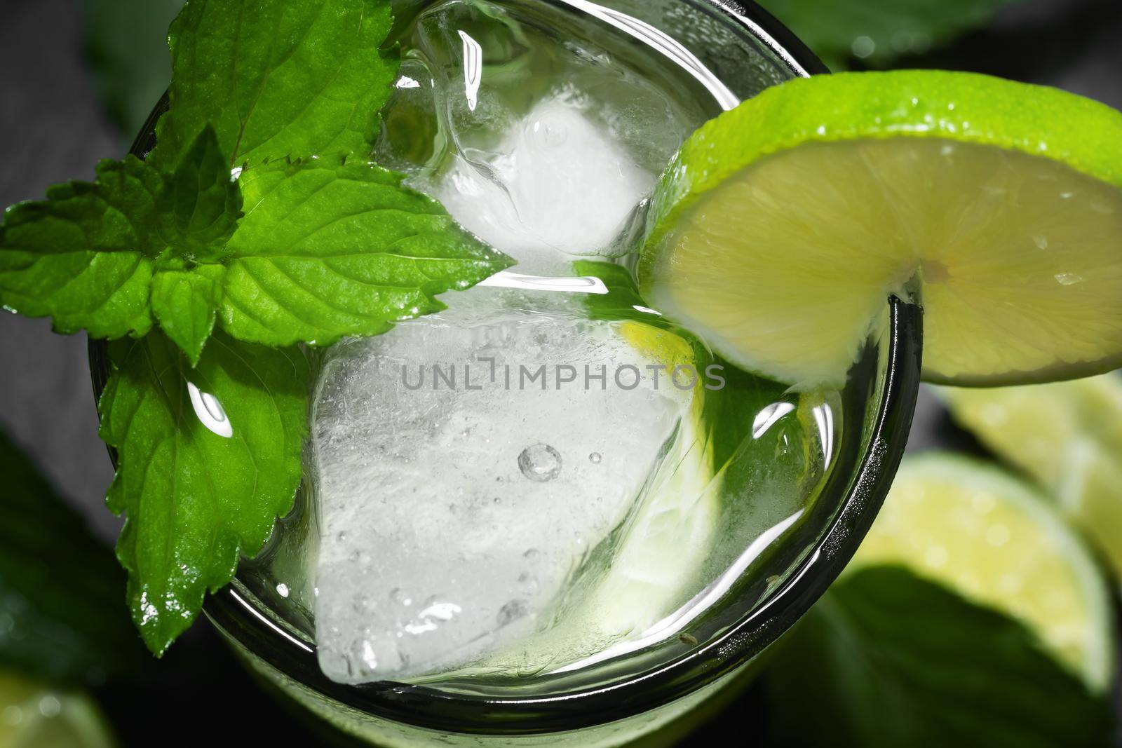 Fresh homemade mojito cocktail with lime, mint and ice on a black background, close-up by galsand