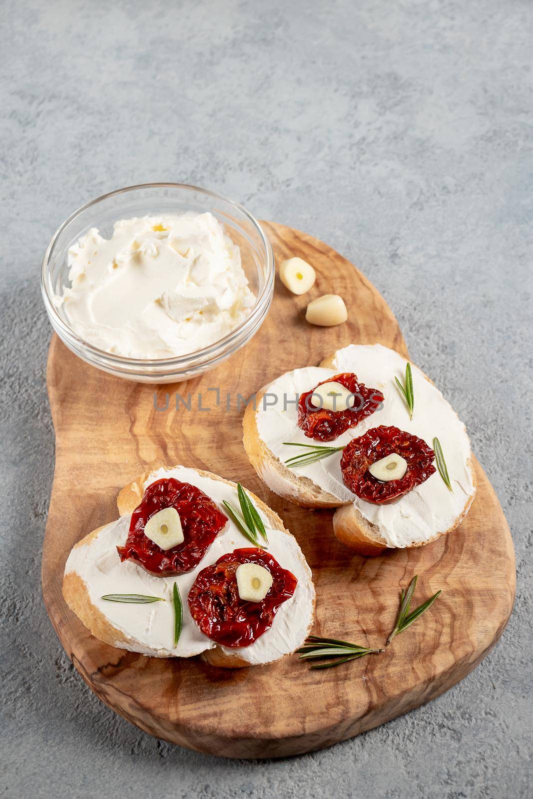 Homemade sandwiches with cream cheese and sun-dried tomatoes on a wooden board of olive - delicious healthy breakfast, italian cuisine, vertical image, copy space.