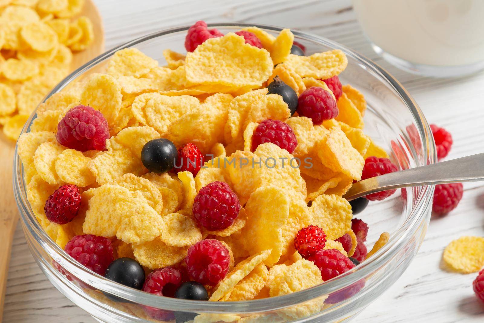 Glass bowl with cereal flakes and berries on the table, close-up.