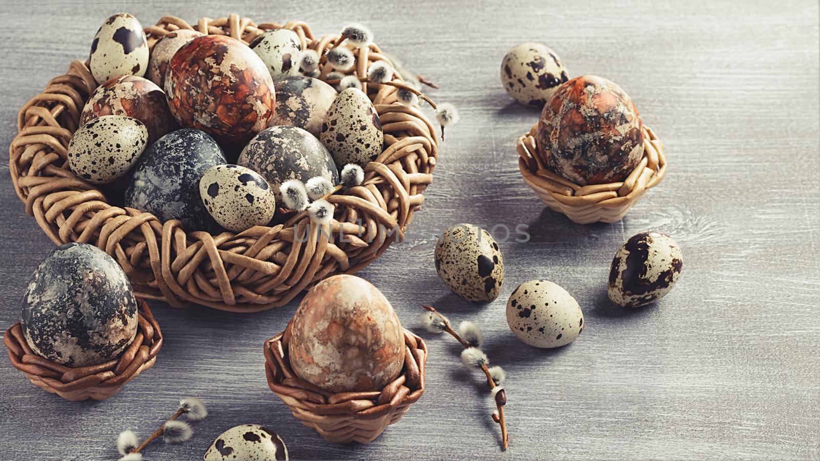 Easter composition - several marble eggs painted with natural dyes in a wicker nest and baskets.