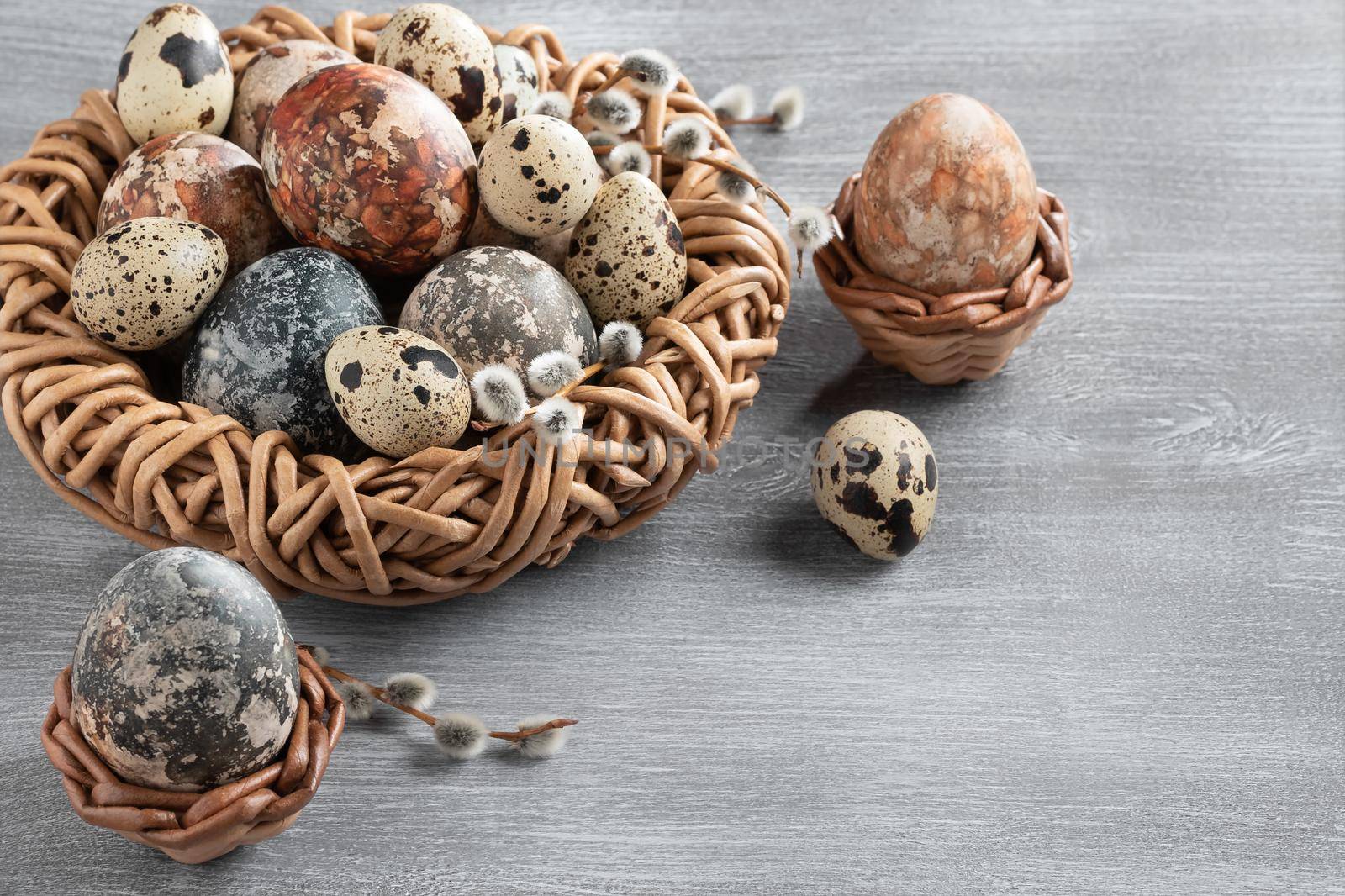Easter composition - several marble eggs painted with natural dyes in a wicker nest and baskets, top view, copy space by galsand