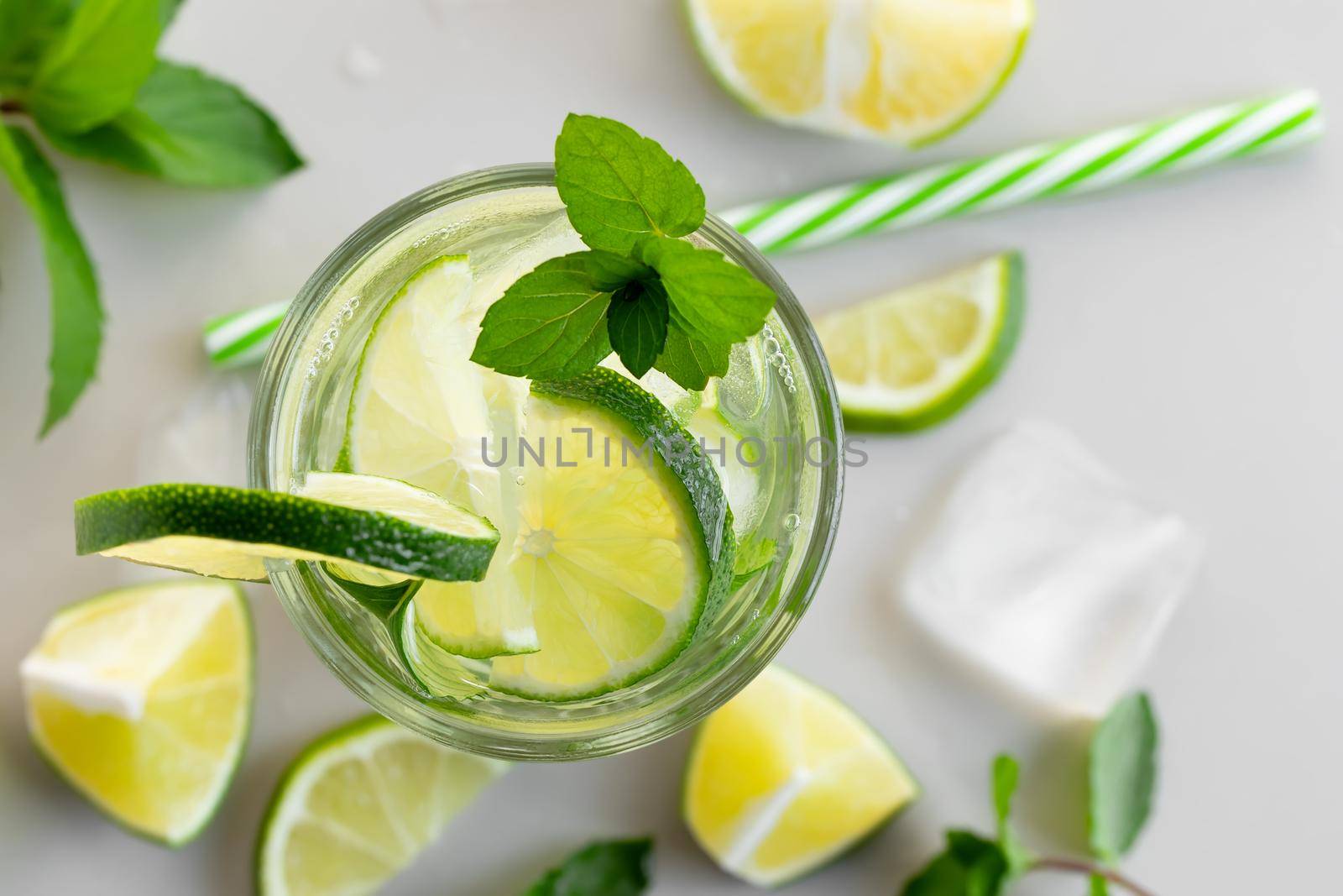 Fresh homemade cocktail with lime, mint and ice on a white table, close up, top view.