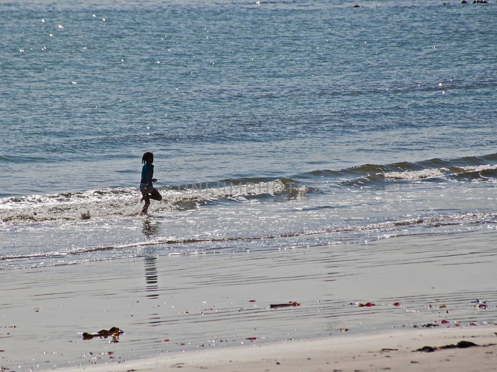 A candid shot of a little girl running in the surf at Hondeklip Bay. South Africa