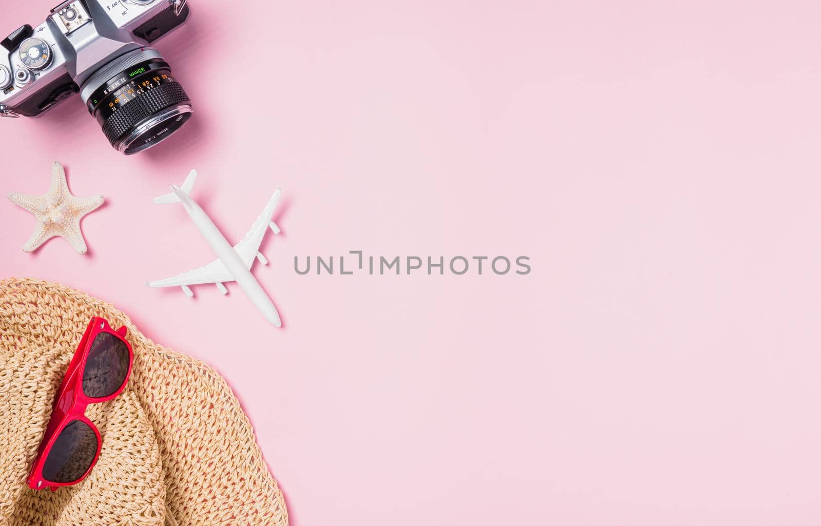 Top view flat lay mockup of retro camera films, airplane, hat, sunglasses, starfish beach traveler accessories on pink background with copy space, Business trip, and vacation summer travel concept
