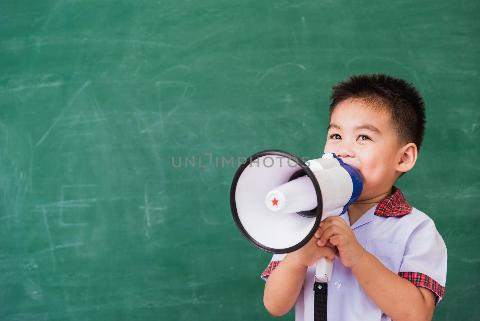 child boy kindergarten preschool in student uniform speaking through megaphone against by Sorapop